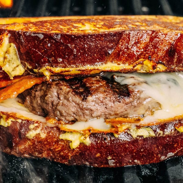 Close-up of a Foodys Tampa burger with melted cheese and bacon between two slices of French toast.